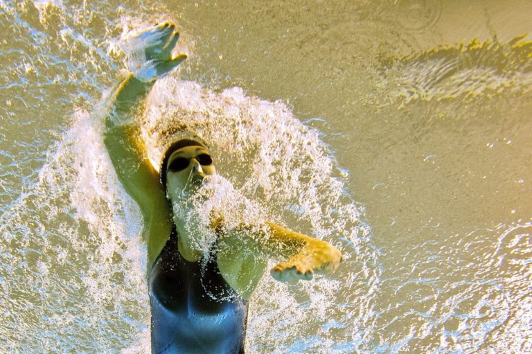 Allison Schmitt an Olympic swimmer mid stroke in the pool shown from an underwater angle.
