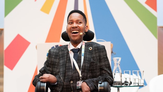 Image of Eddie Ndopu a black man wearing a suit sitting in a wheelchair.