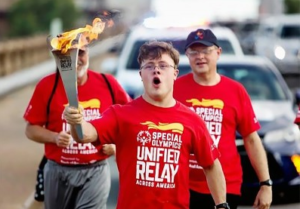 A young man in a red t-shirt carrying the torch that will signal the start of the games.